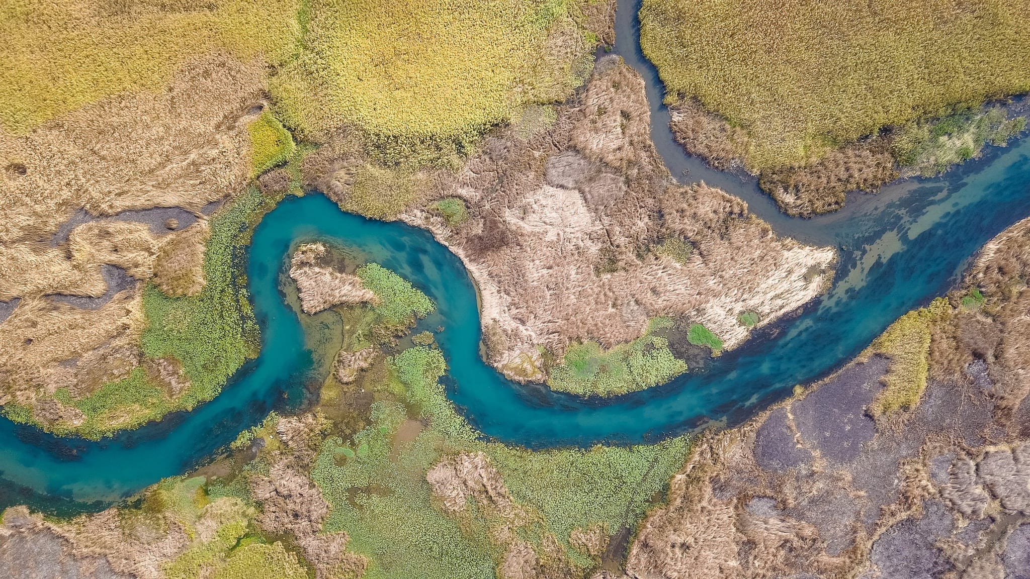Aerial view looking straight down on a blue river curving through open moorland