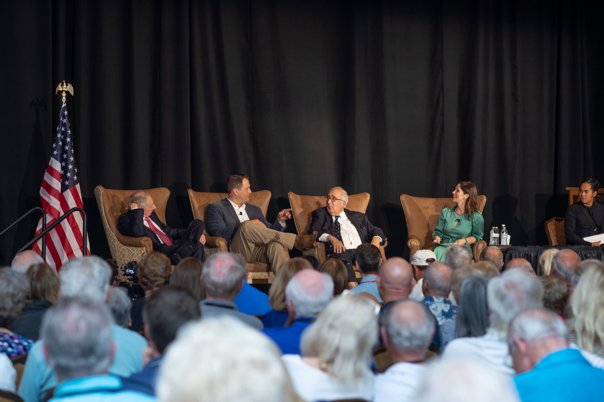 Principals in conversation on stage before a full audience at an investor event